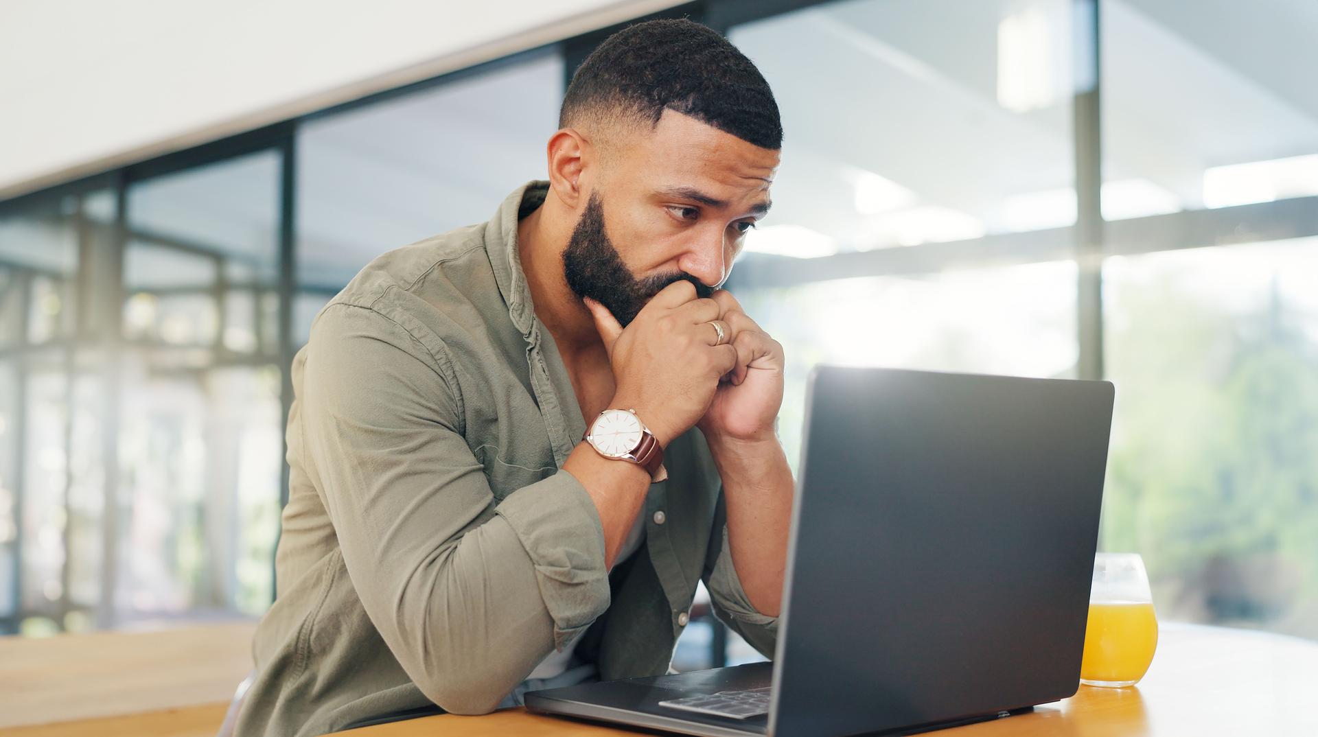 Remote work from home, man and laptop reviewing the FAQ at Sage Collective, intense and focused