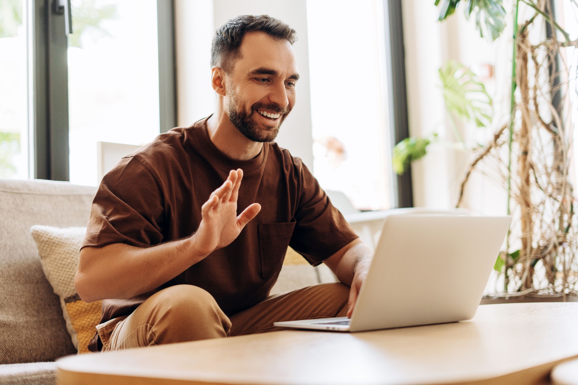 Bearded man using laptop to join a Grove in Sage Collective waving hand